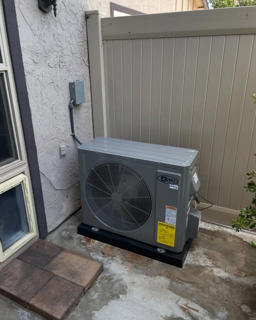 AC condenser installed on a raised pad in a side yard